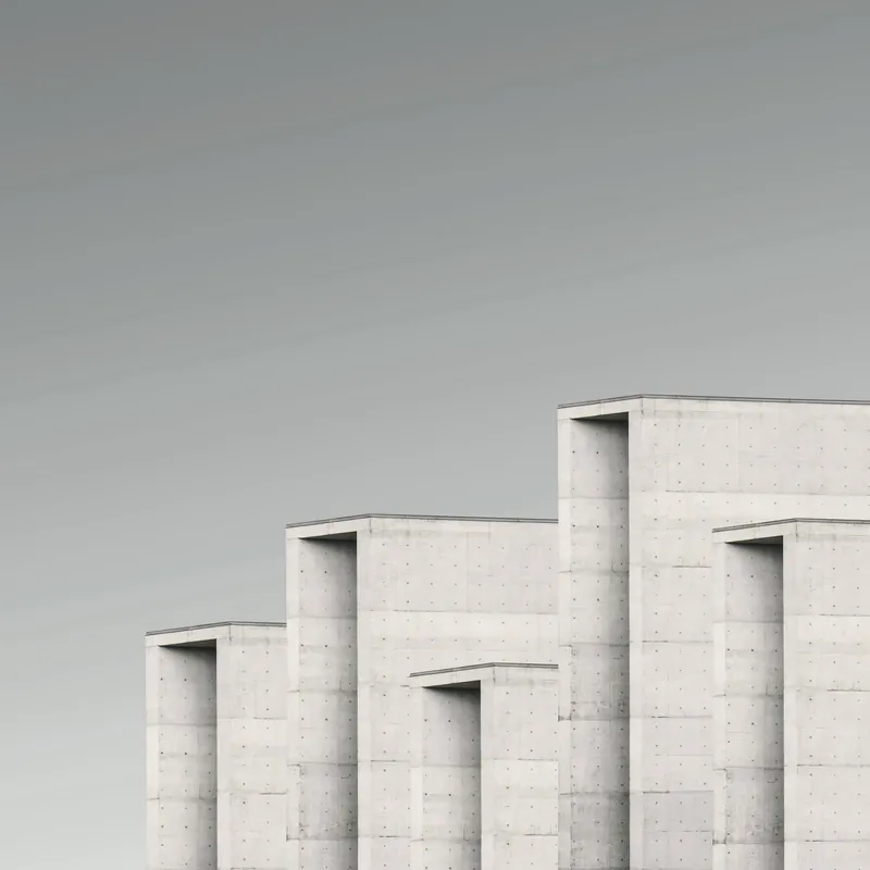 Détail de volumes de béton en gradins sous un ciel pâle.